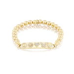 Gold beaded bracelet with ID tag set with icons including peace symbol, daisy, heart, butterfly and horse shoe.