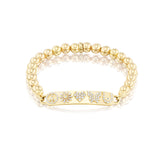 Gold beaded bracelet with ID tag set with icons including peace symbol, daisy, heart, butterfly and horse shoe.